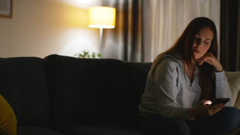 Woman-Sitting-On-Sofa-At-Home-At-Streaming-Or-Watching-Movie-Or-Show-Or-Scrolling-Internet-On-Mobile-Phone-15